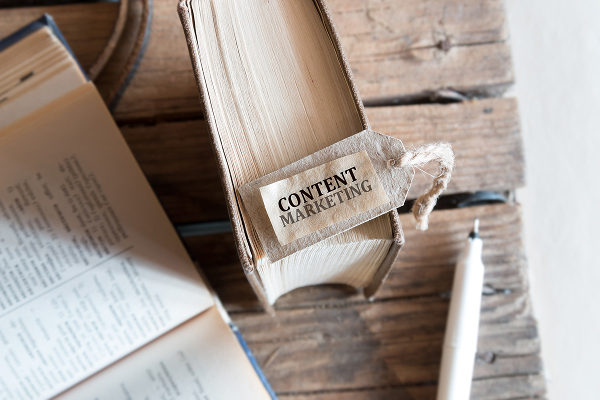 木の机に置かれた本の上にCONTENT MARKETINGと書かれたしおりが乗っている画像