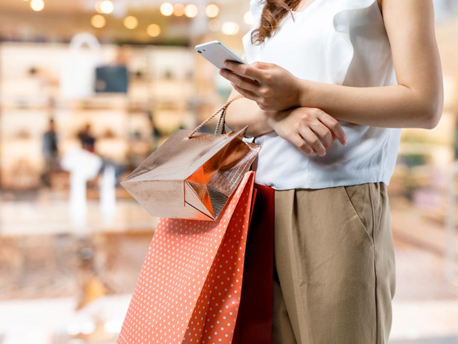 買い物中にスマートフォンを見る女性