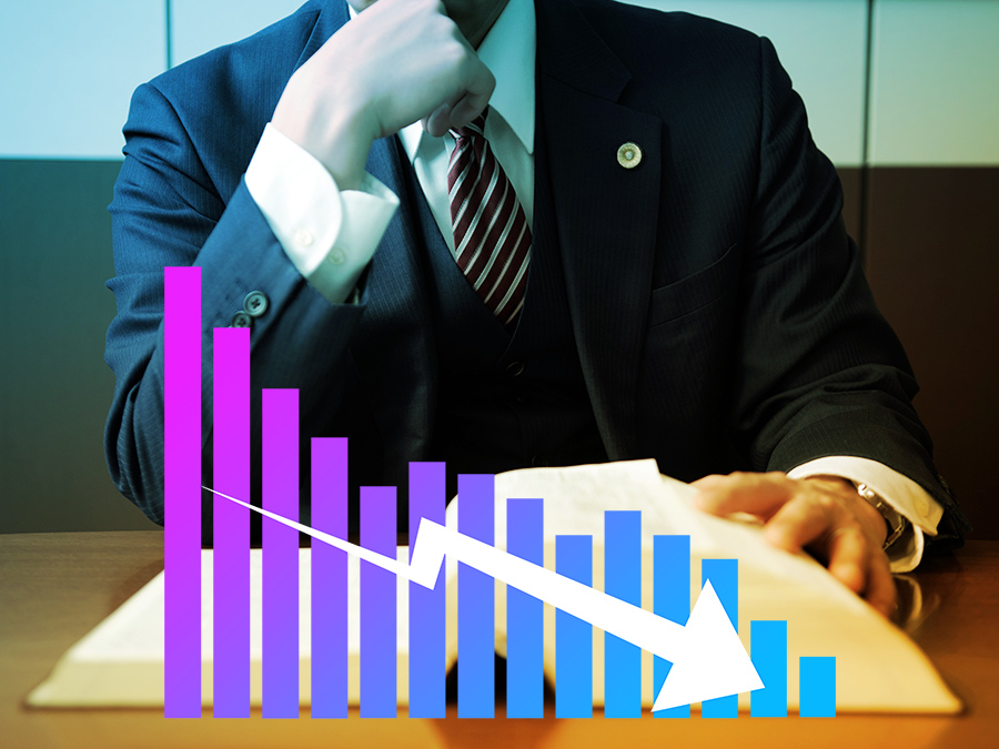 下降するグラフを見て考える男性