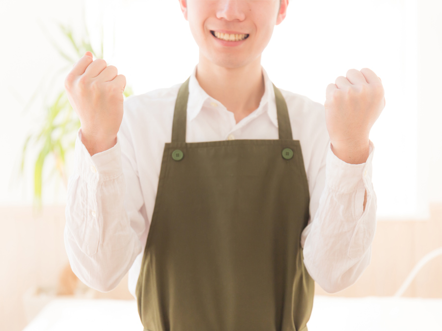 エプロン姿でガッツポーツする男性